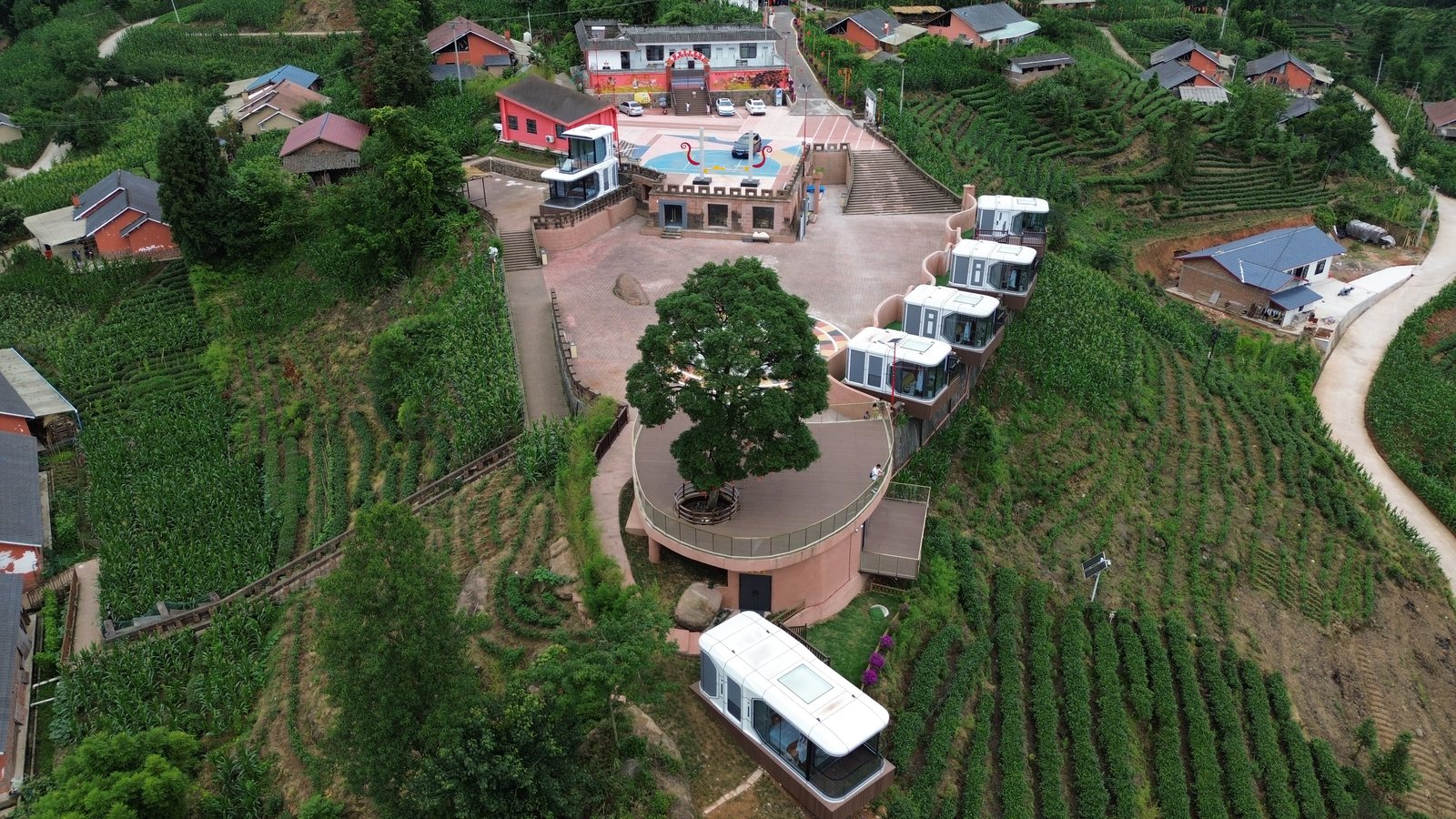 Aerial view of capsule cabins installed around a hillside resort courtyard