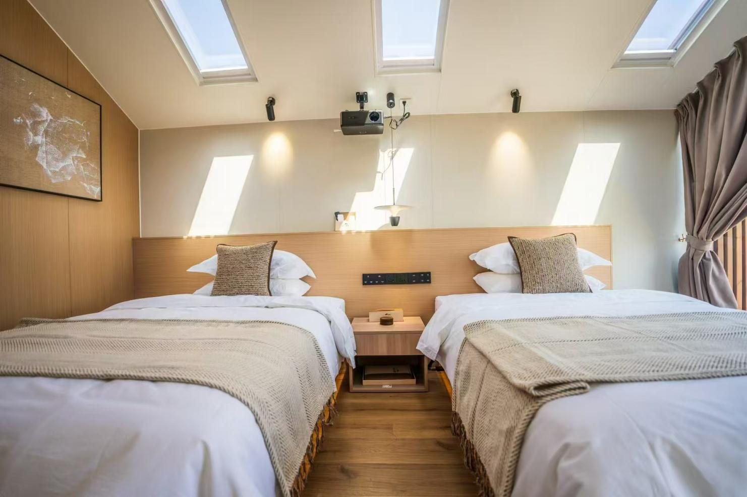 Twin bed capsule cabin interior with skylights and wall-mounted projector