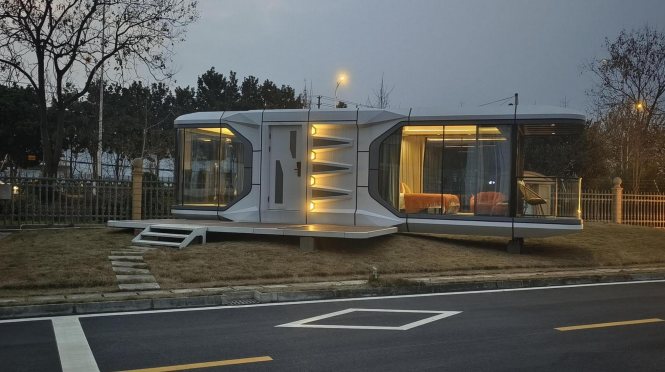 Installed capsule cabin beside a road with lights on at dusk