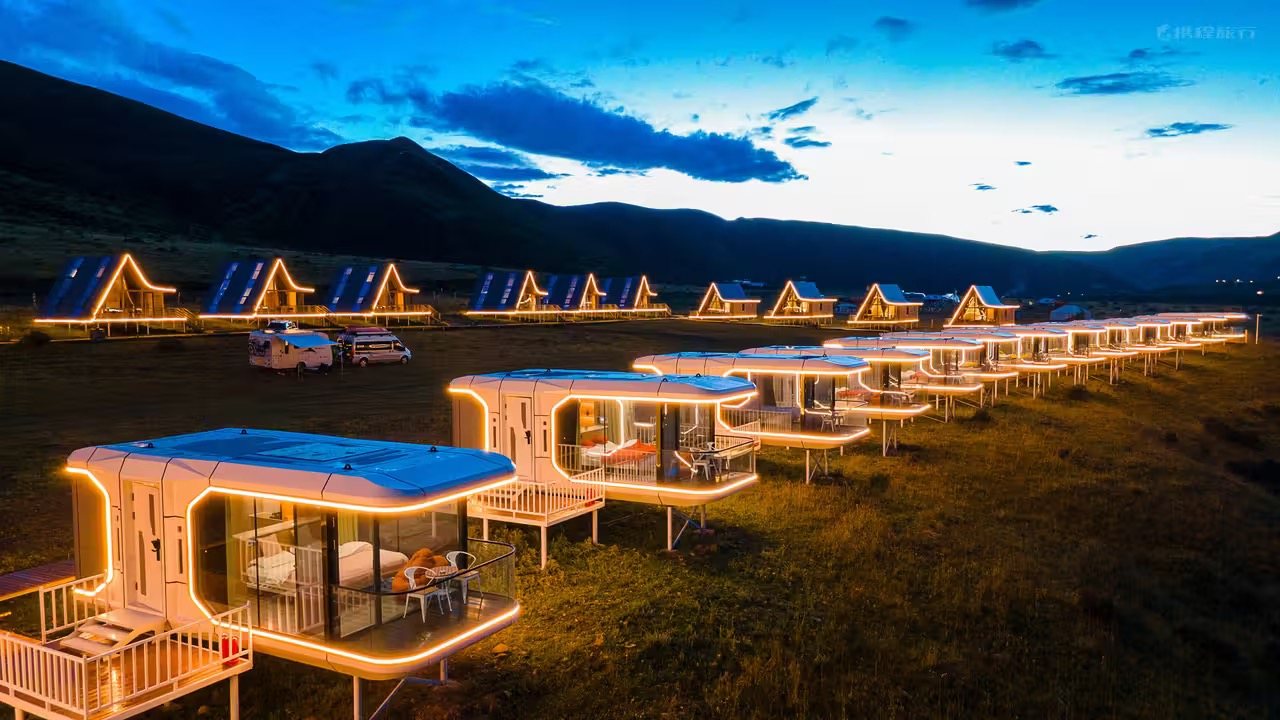 Row of illuminated capsule cabins at a mountain campsite at dusk