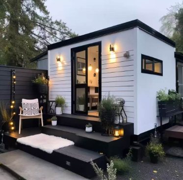 Small backyard guest cabin with steps, patio lights, plants, and open glass door